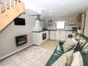 a living room with a couch and a kitchen at Charlottes Cottage in Bamford