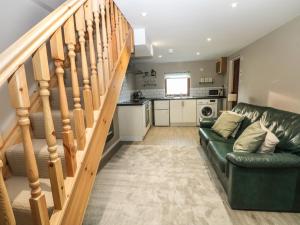 a living room with a green couch and stairs at Charlottes Cottage in Bamford