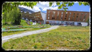 un campus avec un grand bâtiment et une pelouse dans l'établissement les 3 marmottes - Les Arolles, à Bourg-Saint-Maurice