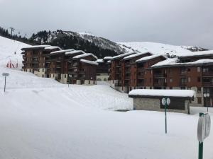 a snow covered parking lot in front of a building at Le Mottet -Prariond - ESF & Skis aux pieds in Valmorel