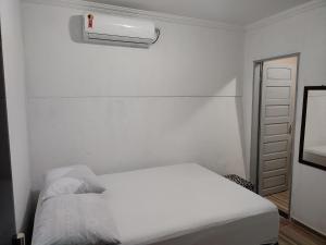 ein weißes Schlafzimmer mit einem Bett und einer Klimaanlage in der Unterkunft Suites Recanto dos Coqueirais Beach in Japaratinga