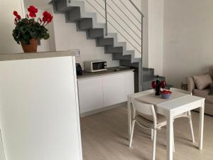 una mesa blanca y sillas en una sala de estar con una escalera en Dimora Cappellini, en Brindisi