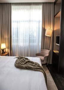 a bedroom with a bed and a chair and a window at The Norman Tel Aviv in Tel Aviv