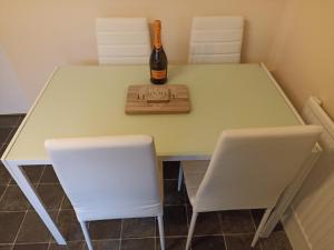 Una botella de champán sentada en una mesa con dos sillas blancas en Comfortable Billericay Home, en Billericay