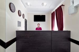 モスクワにあるРОС ОТЕЛЬ Измайловоの部屋のカウンターの後ろに立つ女