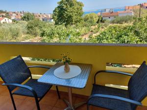 una mesa con 2 sillas y un jarrón con flores en el balcón en Rooms Mediterranean Gardens, en Preko