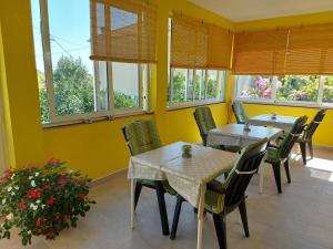 a dining room with tables and chairs and windows at Rooms Mediterranean Gardens in Preko