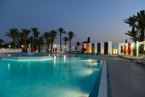 a swimming pool at night with palm trees and buildings at One Resort Aqua Park in Monastir