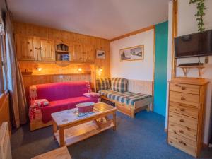 ein Wohnzimmer mit einem roten Sofa und einem Stuhl in der Unterkunft Appartement Valmorel, 1 pièce, 4 personnes - FR-1-356-194 in Valmorel