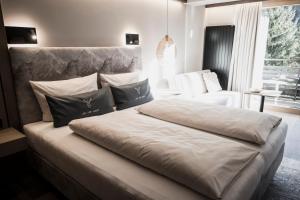 ein Schlafzimmer mit einem großen Bett und einem weißen Stuhl in der Unterkunft Verwöhn-Wellnesshotel Walserhof in Hirschegg