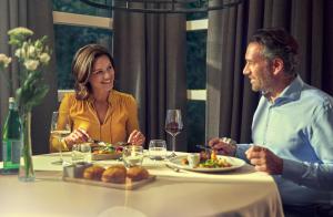 a man and woman sitting at a table with plates of food at Badhotel Renesse in Renesse