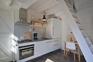 a kitchen with white cabinets and a stove top oven at Vakantiehuisje Lijsterhofstraat 13 - Baddomburg in Domburg