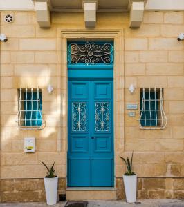 a blue door on a building with two windows at Ta' Ġilard - Lovely Renovated Holiday Home in Żabbar
