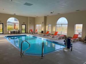 a pool in a hotel with chairs and tables at Wingate by Wyndham Clearfield in Clearfield