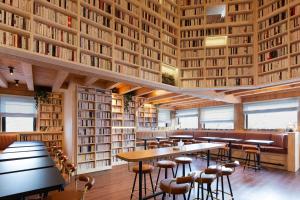 een bibliotheek met tafels en stoelen en boekenplanken bij Ours Blanc Hotel & Spa in Les Menuires