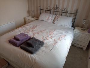 1 cama con 2 toallas y 2 almohadas en Comfortable Billericay Home, en Billericay