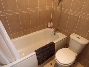 a bathroom with a toilet and a bath tub with a toilet at Comfortable Billericay Home in Billericay