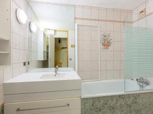 uma casa de banho com um lavatório, uma banheira e um espelho. em Appartement Valmorel, 2 pièces, 5 personnes - FR-1-356-201 em Valmorel