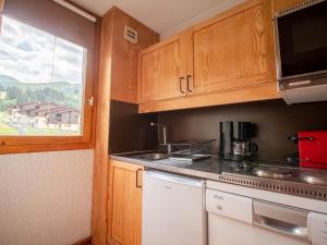 eine kleine Küche mit Holzschränken und einem Fenster in der Unterkunft Appartement Valmorel, 2 pièces, 5 personnes - FR-1-356-290 in Valmorel