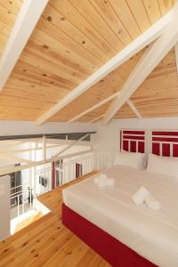 una camera da letto con un grande letto bianco e soffitti in legno di Ether Loft Suites ad Atene