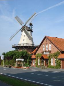 a windmill in front of a building with a house at Zur Querensteder Mühle in Bad Zwischenahn