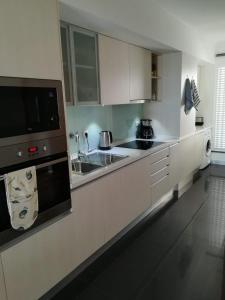 uma cozinha branca com um lavatório e um micro-ondas em Tamariz Flat em Santa Cruz - Madeira