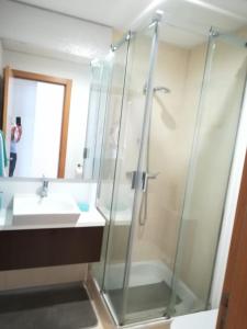 a bathroom with a glass shower and a sink at Tamariz Flat in Santa Cruz