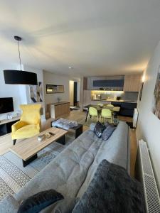 a living room with a gray couch and a yellow chair at Olimpijska kuca 202 in Jahorina