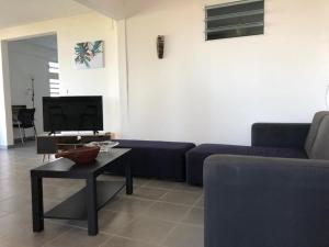 a living room with a blue couch and a table at 3soleils in Schœlcher