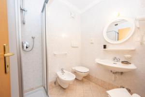 a bathroom with a toilet and a sink and a shower at Flos Hotel in Moena