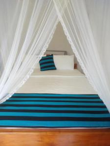 Una cama con dosel con rayas azules y blancas en Elegant Home Stay, en Ella