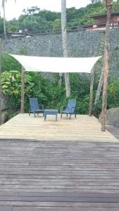two blue benches on a wooden deck with a white canopy at Suítes home paraíso no norte in Ilhabela