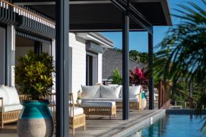 un patio con muebles blancos junto a una piscina en Les villas de Sweet Hill, en Saint Barthelemy