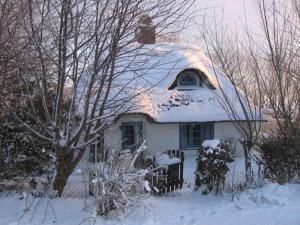 uma casa branca com neve no telhado em Ferienkate Kap Eiderstedt em Westerhever