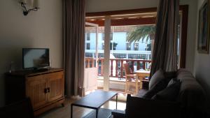 een woonkamer met een bank, een televisie en een balkon bij Apartment in the City Center near to the beach in Puerto del Carmen