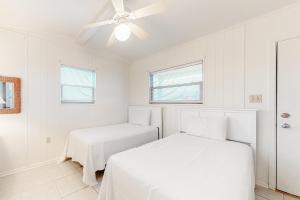two beds in a white room with a ceiling fan at Campbellot by Meyer Vacation Rentals in Fort Morgan