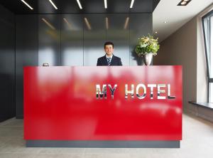 Un uomo è dietro un cartello rosso dell'hotel di Myhotel a Künzelsau