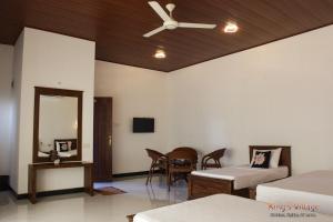 a room with two beds and a table and a ceiling fan at Kings Village Sigiriya in Sigiriya