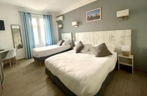 a hotel room with two beds and a desk at Hotel Les Palmiers En Camargue in Saintes-Maries-de-la-Mer