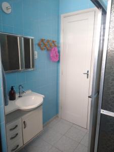 baño con lavabo y puerta blanca en Casa Centro de Peruíbe - R&P, en Peruíbe