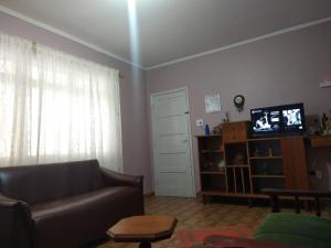 Una sala de estar con un sofá y un televisor. en Casa Centro de Peruíbe - R&P, en Peruíbe