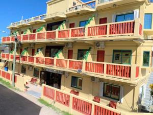 a yellow building with red balconies on a street at Caye Caulker Plaza Hotel in Caye Caulker