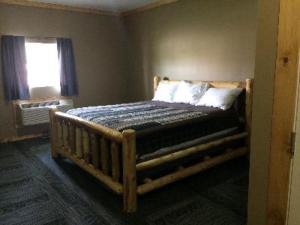 um quarto com uma cama de madeira com almofadas e uma janela em Big Horse Inn and Suites em Lewistown