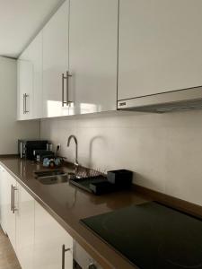 a kitchen with white cabinets and a sink at Art'Estrela in Covilhã