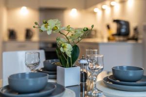 a table with plates and glasses and a vase with flowers at Windsor Luxury Studio Apartment in Windsor