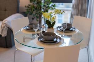a glass table with plates and wine glasses on it at Windsor Luxury Studio Apartment in Windsor