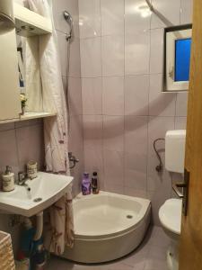 uma casa de banho com uma banheira, um lavatório e um WC. em Apartman "MILLAN 2" em Prijedor