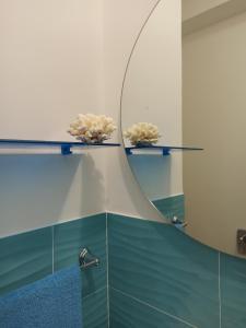uno specchio su un muro con due fiori sopra di Bed&Book 'A parma a Salemi