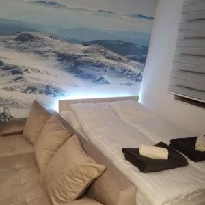a white bed with two towels on top of it at Apartman Ice age Jahorina in Jahorina