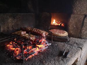 a grill with some meat and a pizza on fire at Hogar Gallán in Gondomar